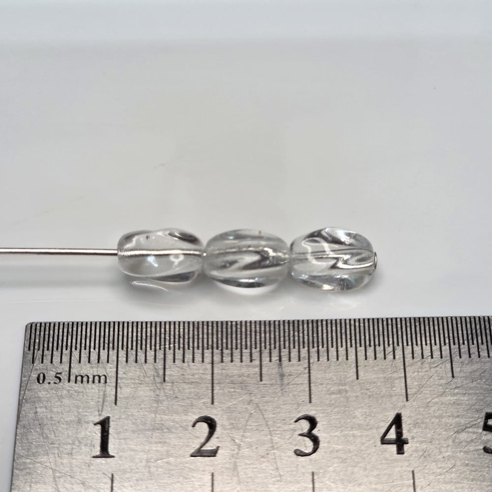 Clear glass beads on a metal rod with a ruler for scale on a white background