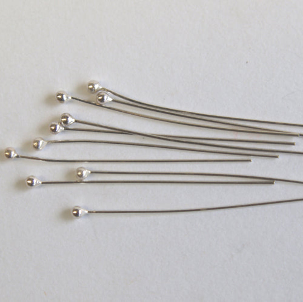 Set of metal pins with silver heads on a light gray background