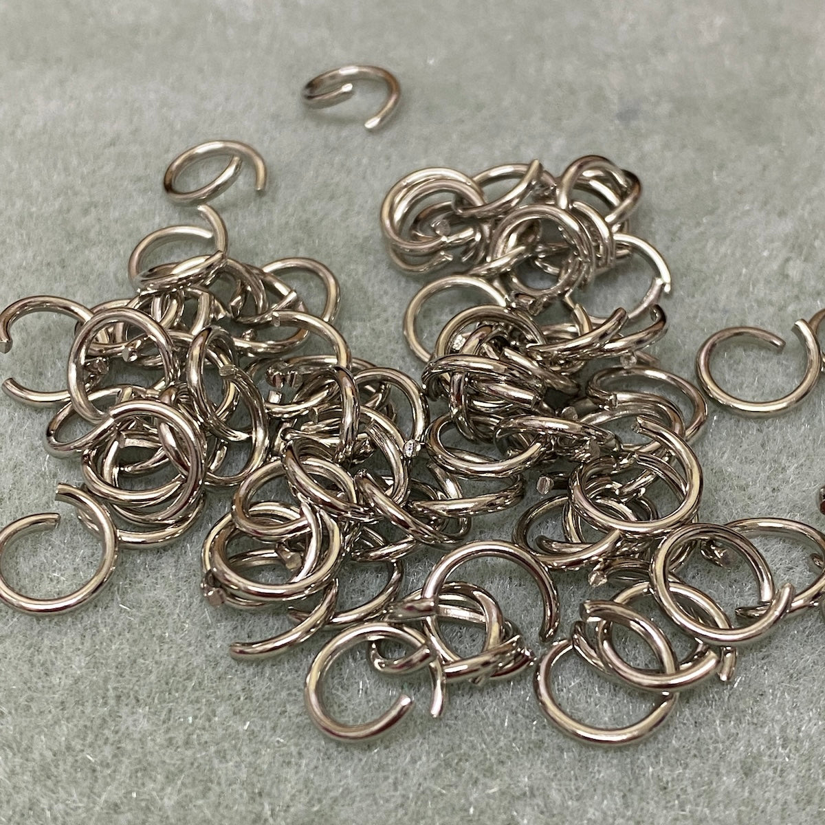 Collection of silver jump rings on a gray surface