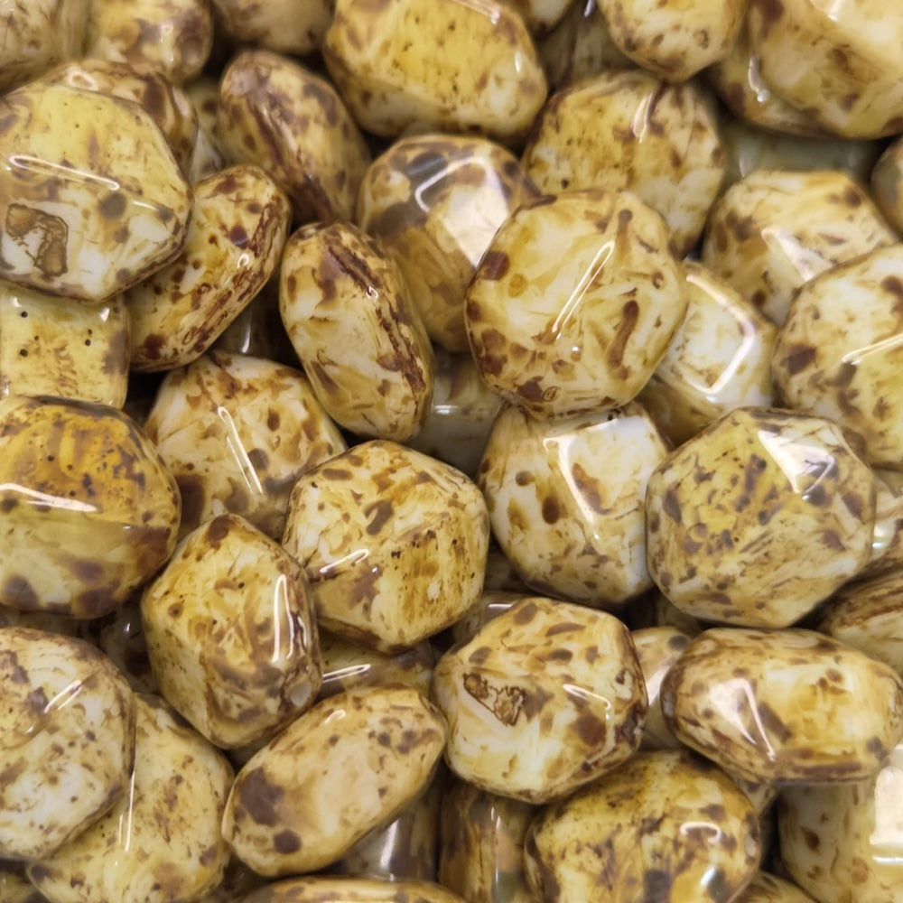 Close-up of a pile of brownish-golden diamond shape beads with dark spots.