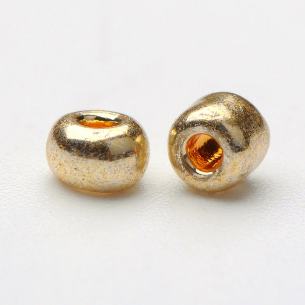 Two gold glass seed beads on a white background