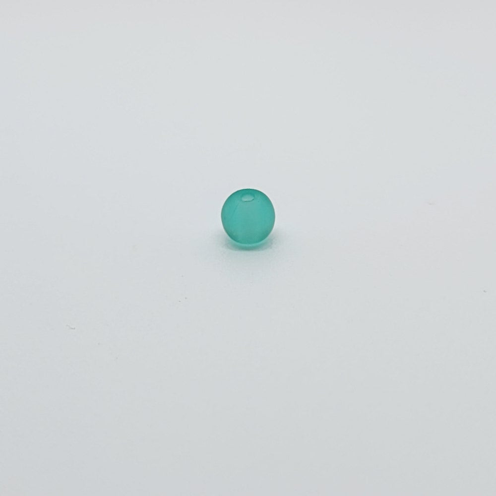 one teal green round vintage glass bead on a white background showing the threading hole