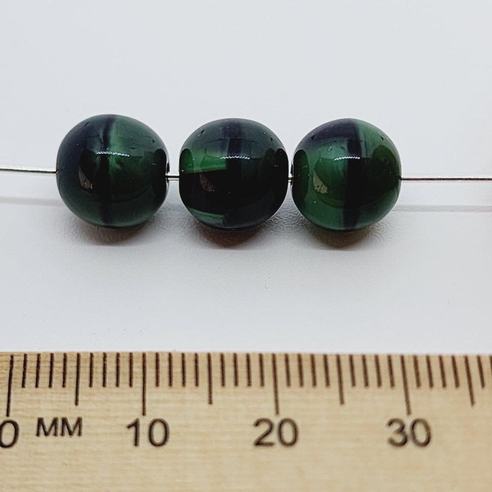 three malachite green and black bead with a ruler to show scale