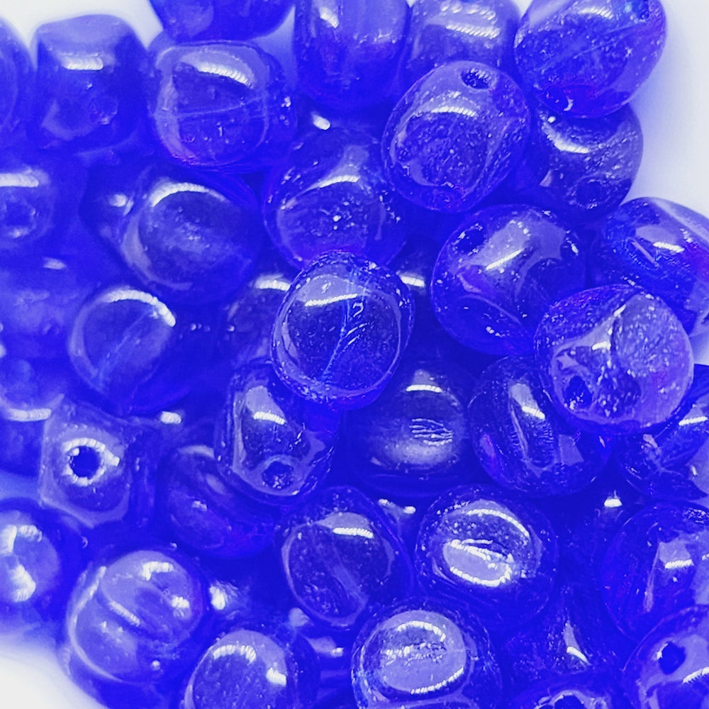 A collection of blue pinched cube-shaped Czech glass beads.