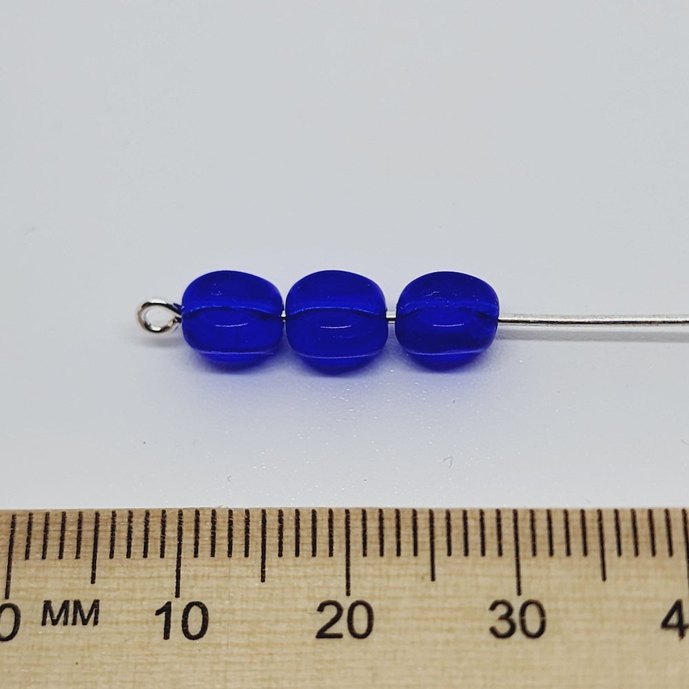 cube blue beads on a pin with a ruler for scale on a white background