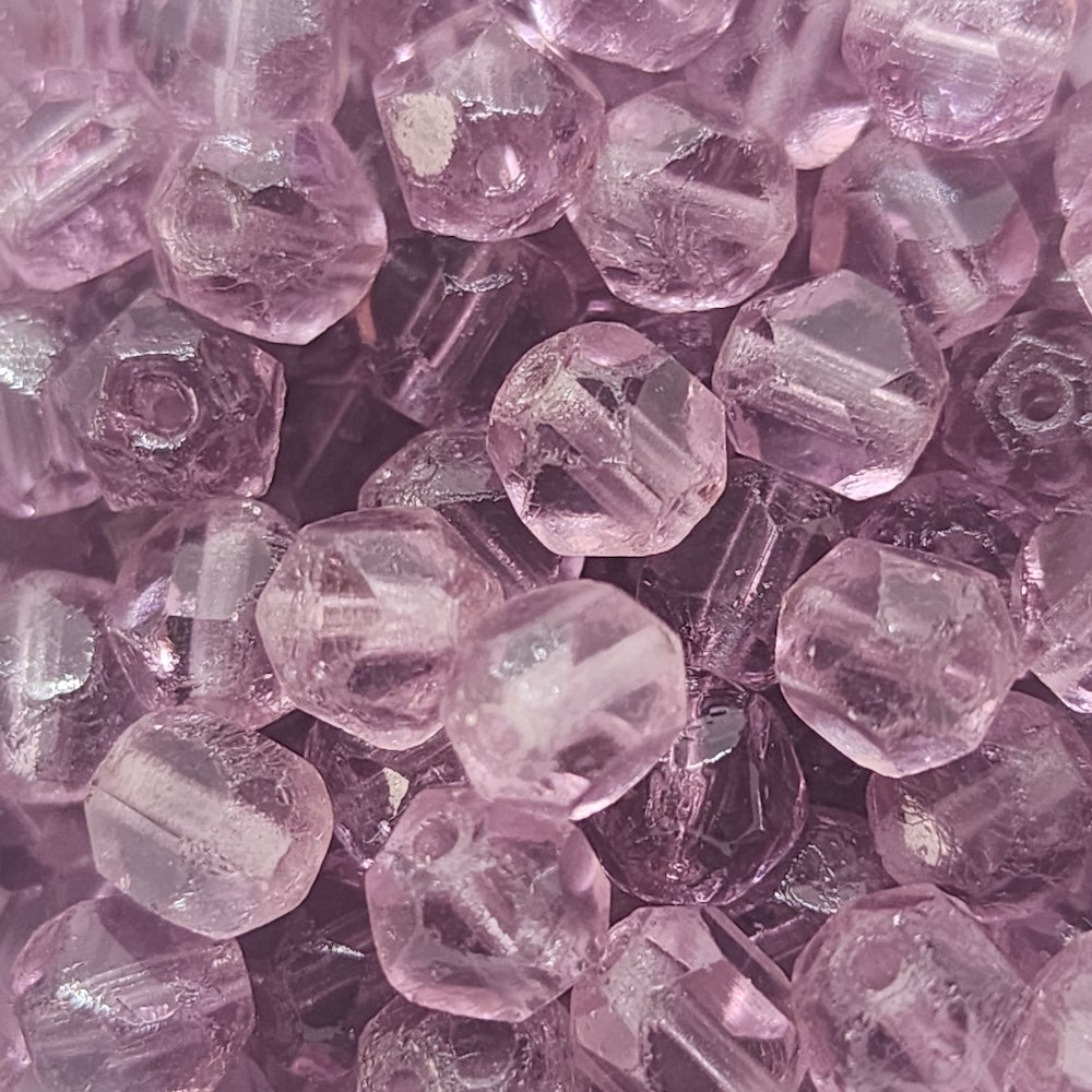 a collection of purple cut glass beads showing the shape of the cuts and the threading holes