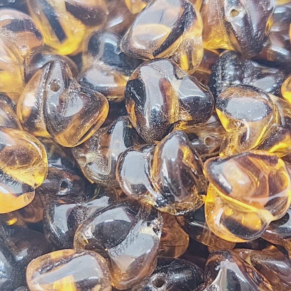 A close-up image of small, twisted, transparent amber-colored Czech glass beads.