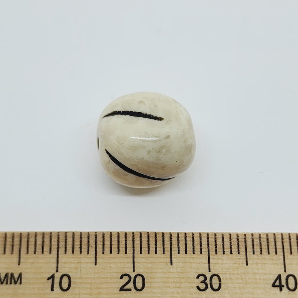 close up stone look beads with large threading hole and a glossy surface with a ruler for scale