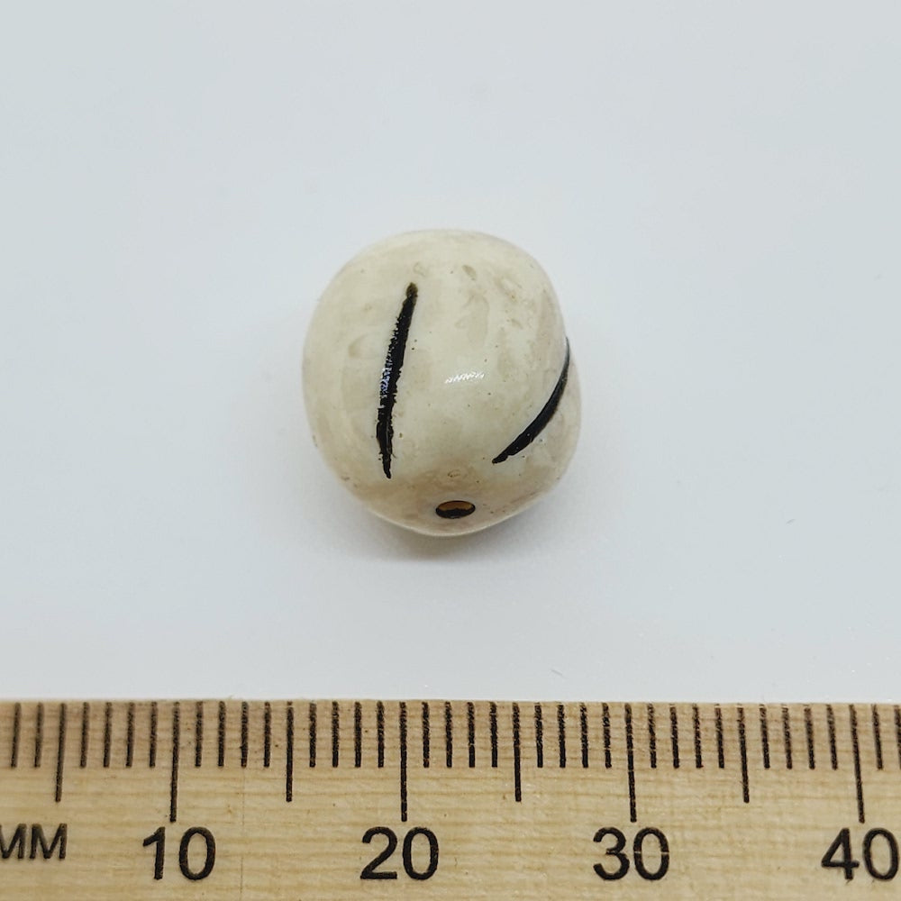 close up stone look beads with large threading hole and a glossy surface with a ruler for scale