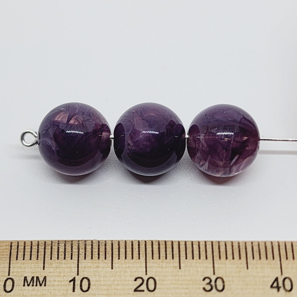 Amethyst purple gemstone style acrylic beads resembling real gemstones, with visible threading holes for crafting jewelry on a white background, used for crafting and jewelry making against a ruler to show the size