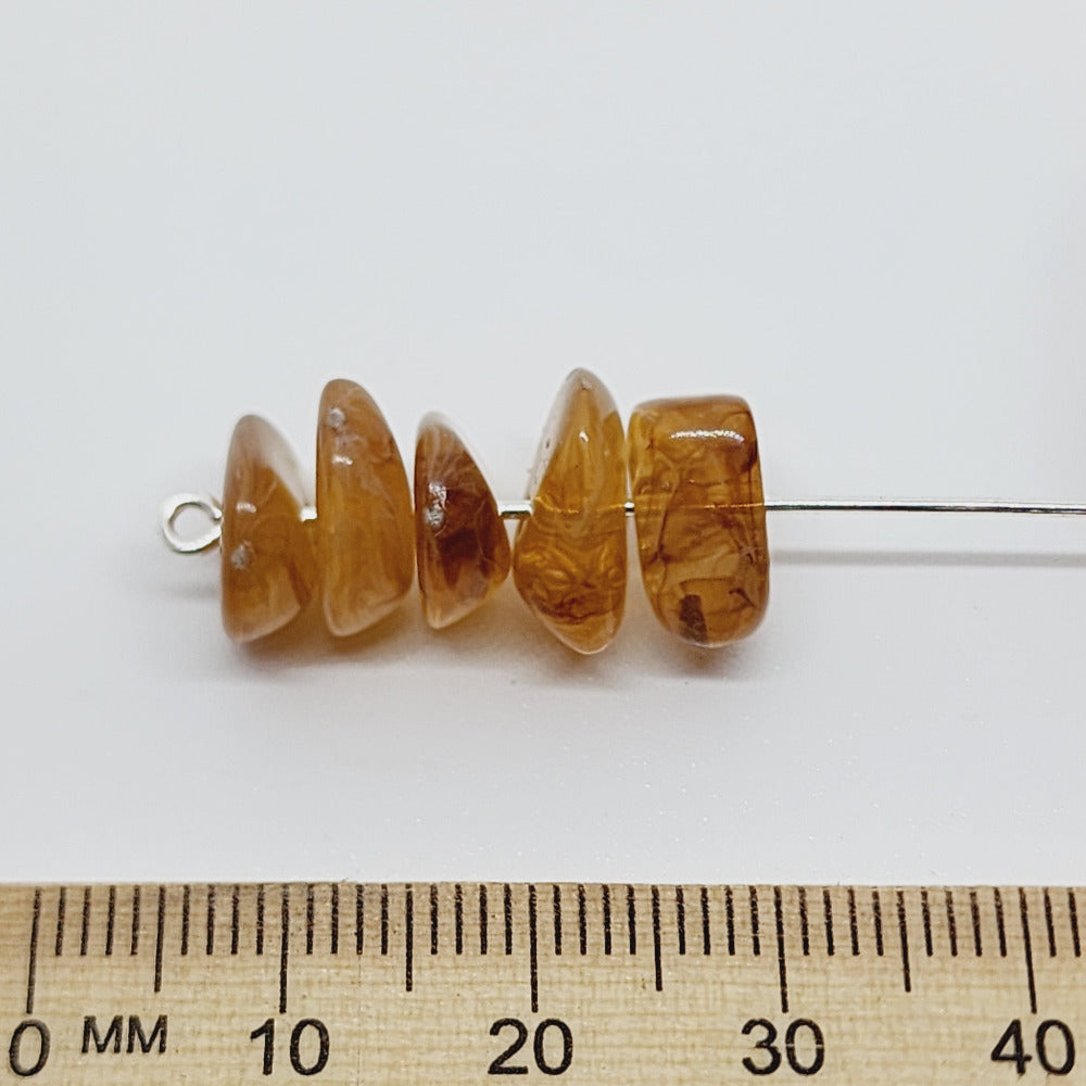 brown jasper gemstone look acrylic beads with visible threading holes for crafting jewelry on a white background against a ruler for scale
