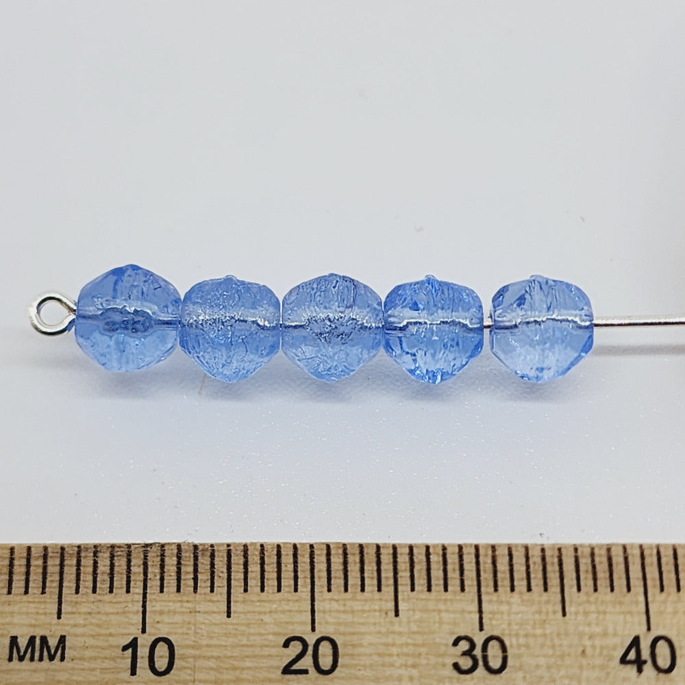Blue glass beads on a stick with a ruler for scale on a white background
