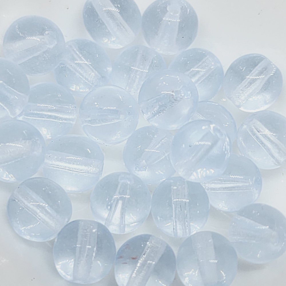 A collection of small, transparent blue Czech glass beads with visible facetting.