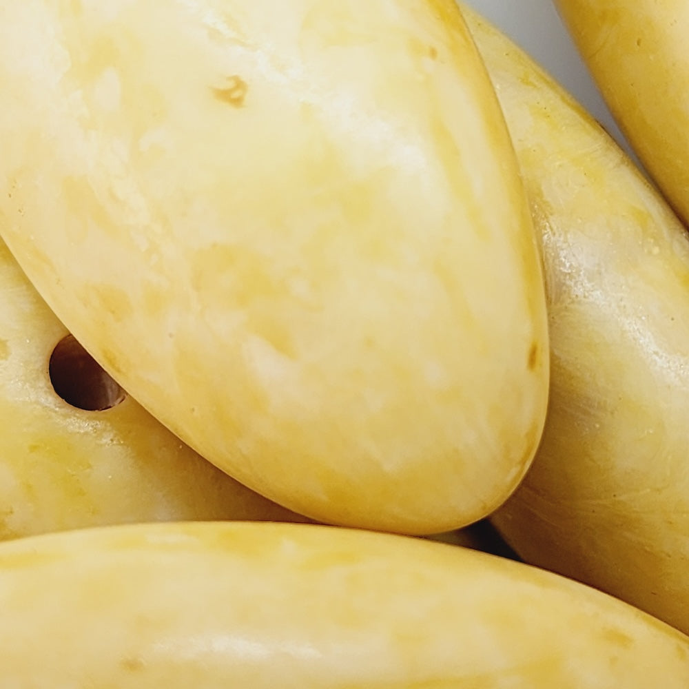 close up of yellow cream drop beads for the purpose of making jewelry or craft
