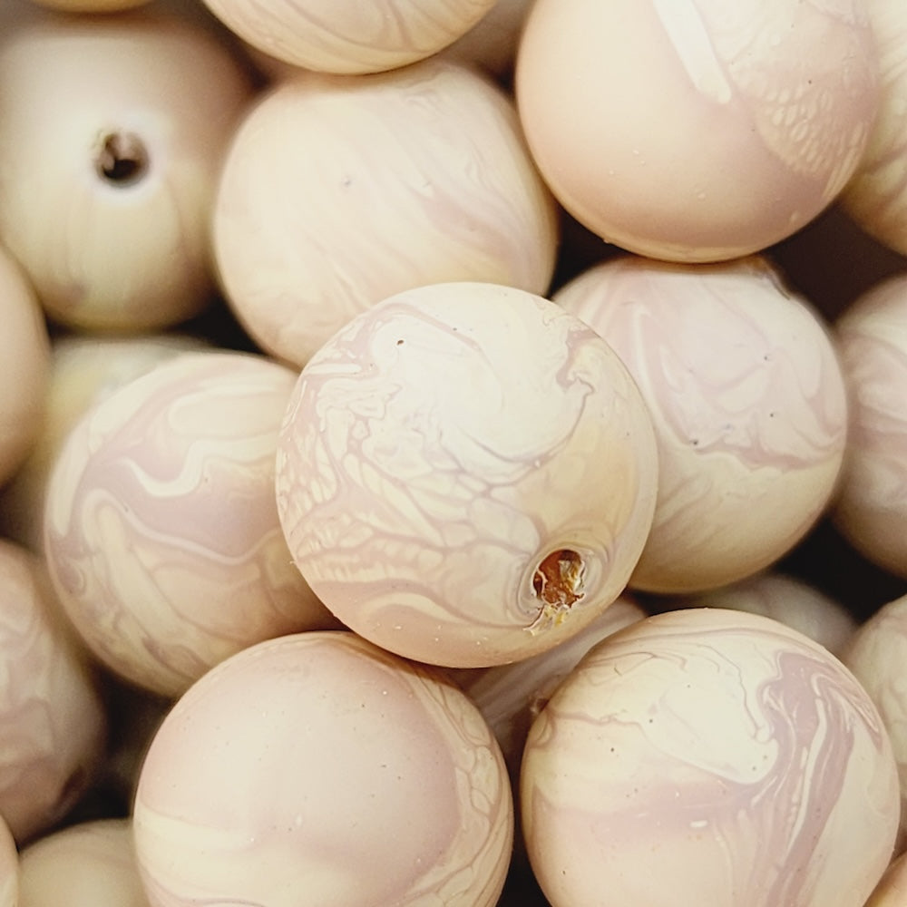 Close-up of marble finish wood look beads with a central hole.
