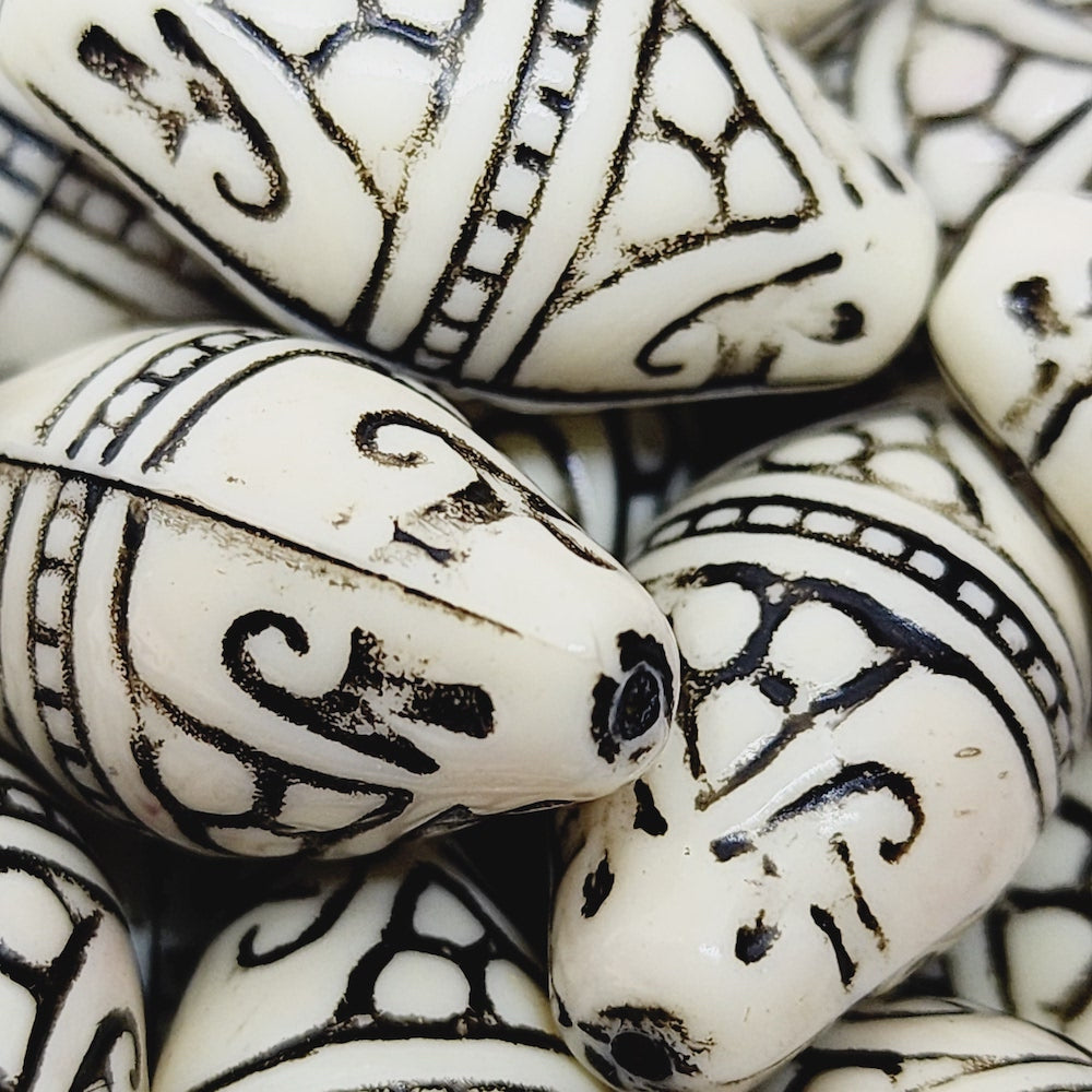 A group of white and black torpedo-shaped lucite bead with geometric Art Deco style etchings for the purpose of making jewelry
