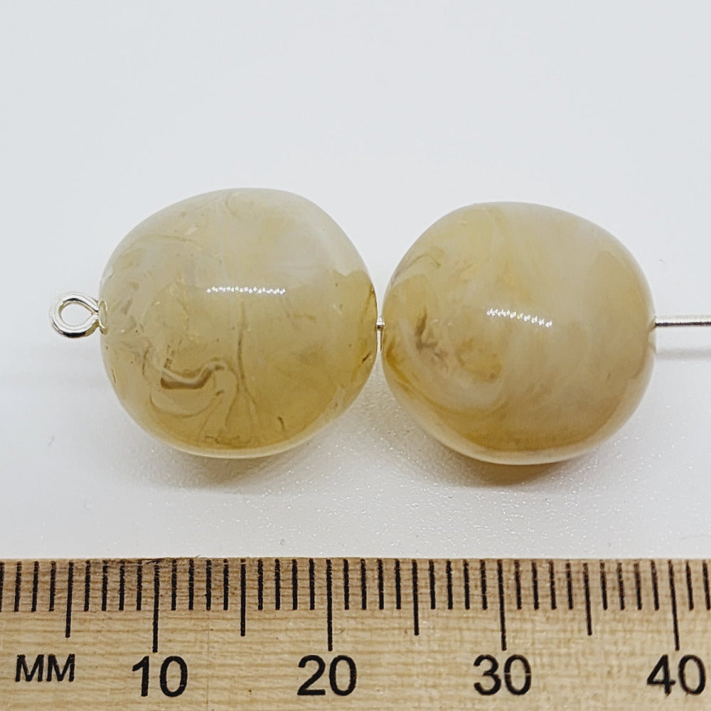 Citrine yellow gemstone style acrylic beads with visible threading holes for crafting jewelry on a white background and a ruler to show scale