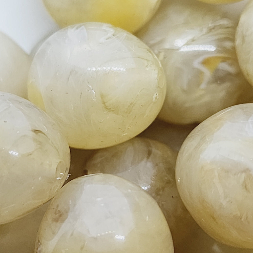 Citrine yellow gemstone style acrylic beads with visible threading holes for crafting jewelry on a white background