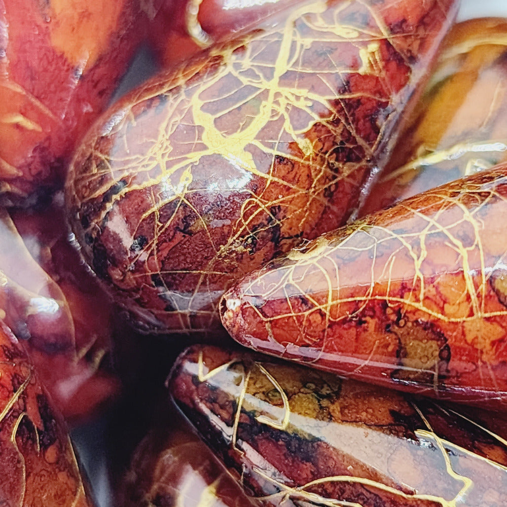 A group of teardrop-shaped vintage Lucite bead with a rust bubble glaze look and gold drizzle patterns,
