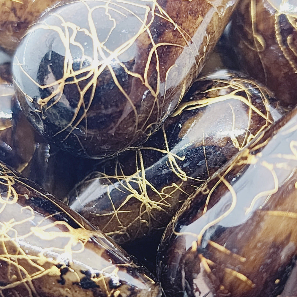 A group of teardrop-shaped vintage Lucite bead in brown with a gold drizzle pattern,