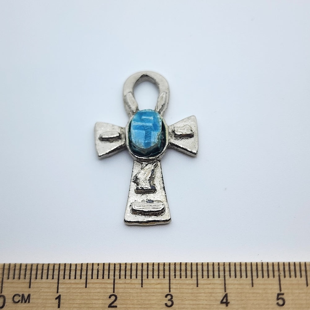 Metal Ankh vintage charm with turquoise blue tiny scarab beetle in the centre on a white background with a ruler for size perception