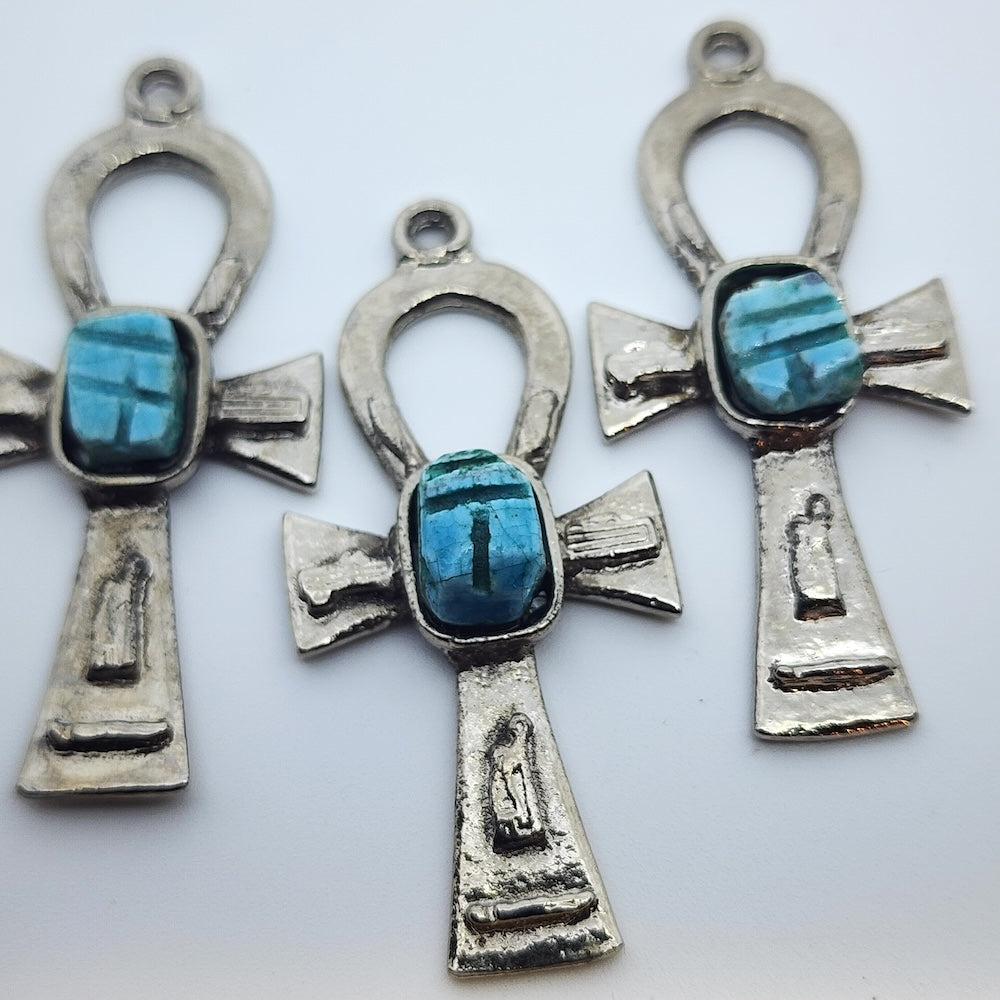 Three Metal Ankh vintage charms with turquoise blue tiny scarab beetle in the centre on a white background