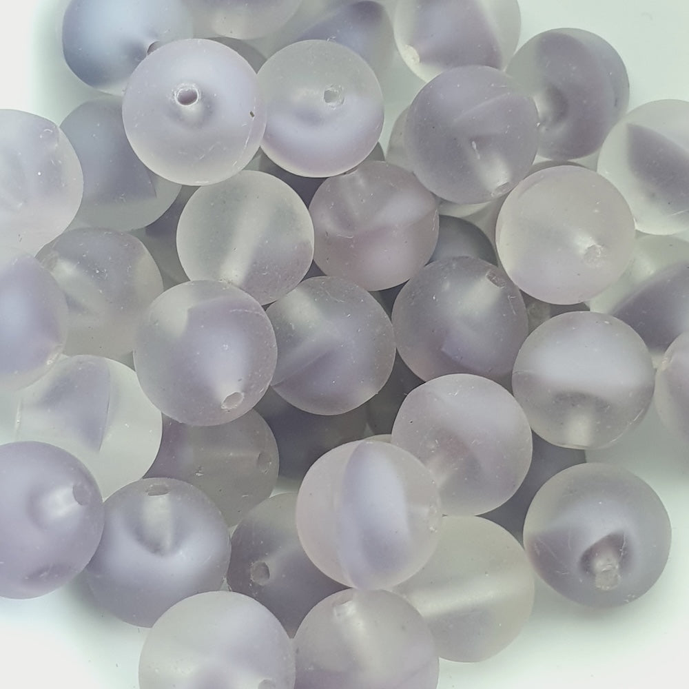 A collection of round, clear glass beads with a milky purple tint.