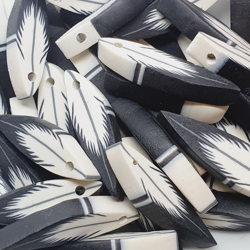 Close-up of black and white feather beads on a textured surface