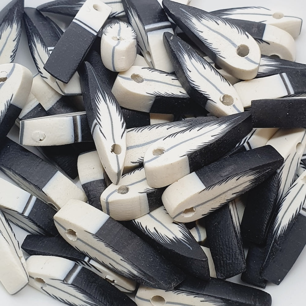 Collection of black and white feather-shaped beads on a white background