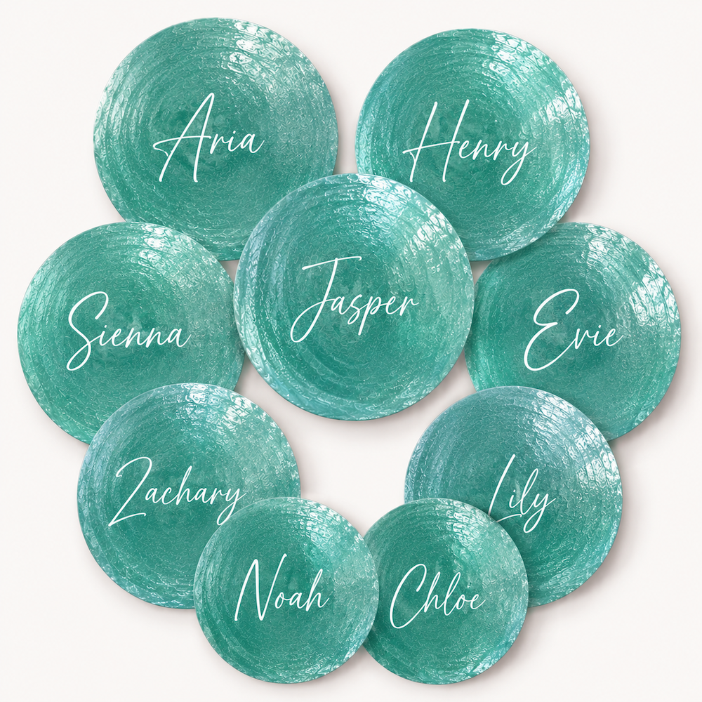 A set of round teal and aqua painted shell name plaques with white script names including Aria, Henry, Sienna, Jasper, Evie, Zachary, Noah, Chloe, and Lily, arranged in a circle on a light beige background.