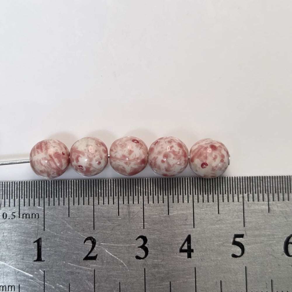 Marbled pink and white beads on a ruler for size reference