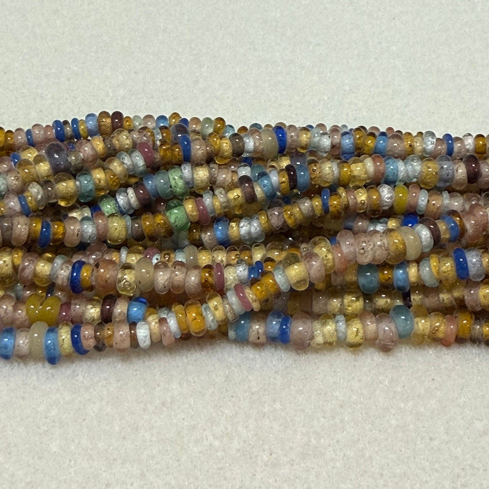 Multicolored donut shaped Indonesian glass bead strands on a white background