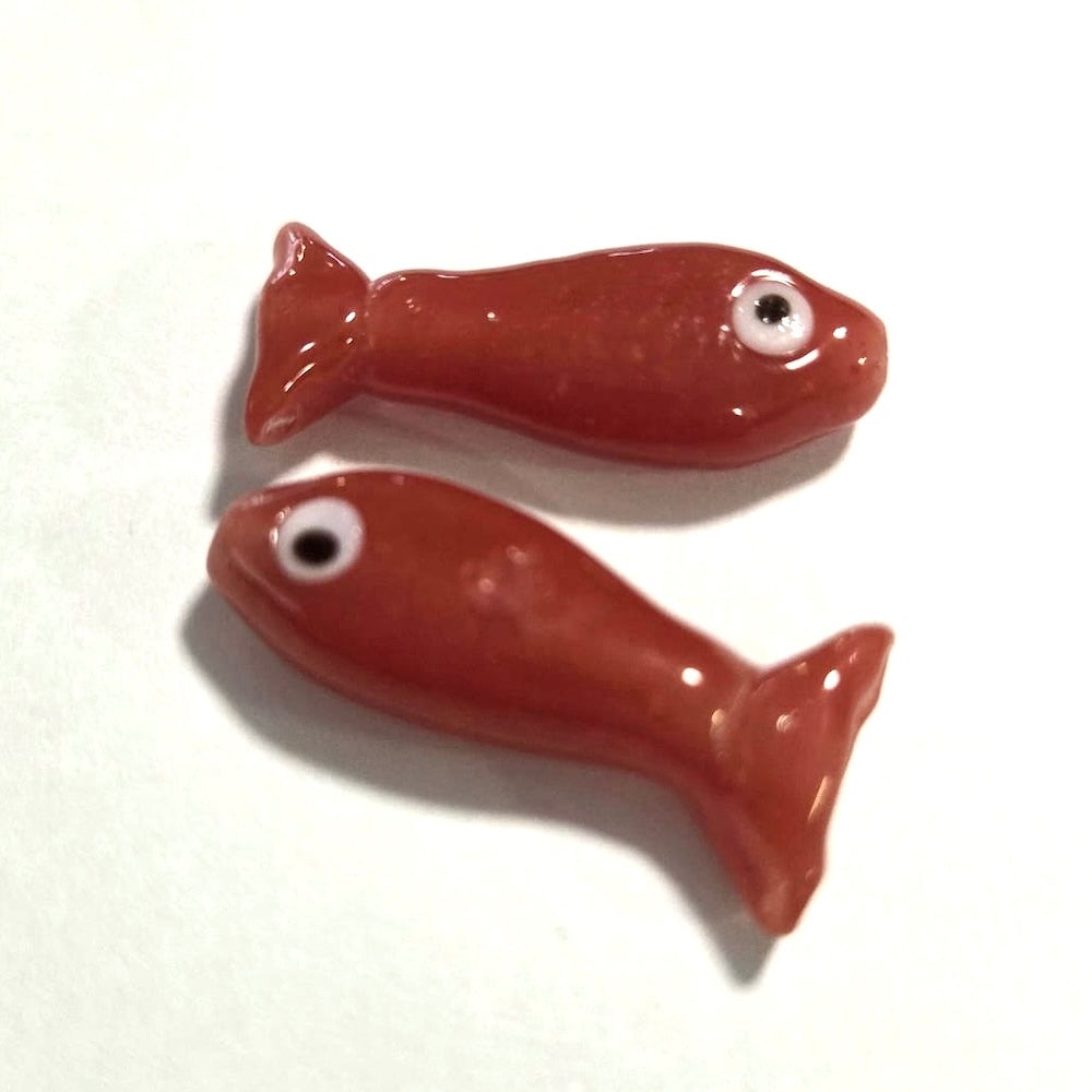 Two red glass sardine fish on a white background