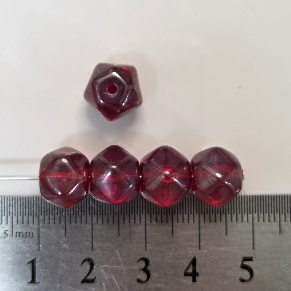 Red faceted beads on a ruler for size reference