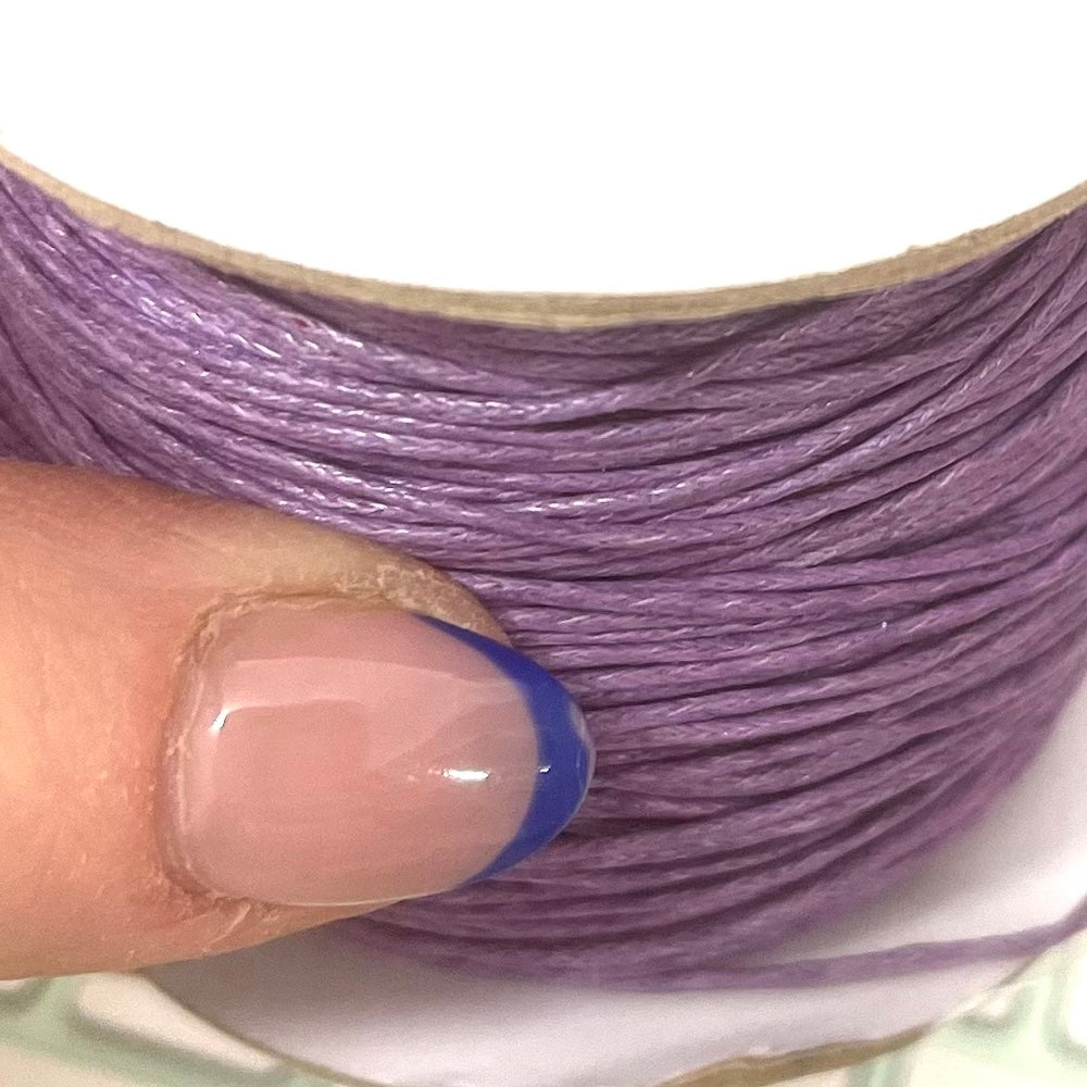 Close-up of a hand holding a spool of purple thread