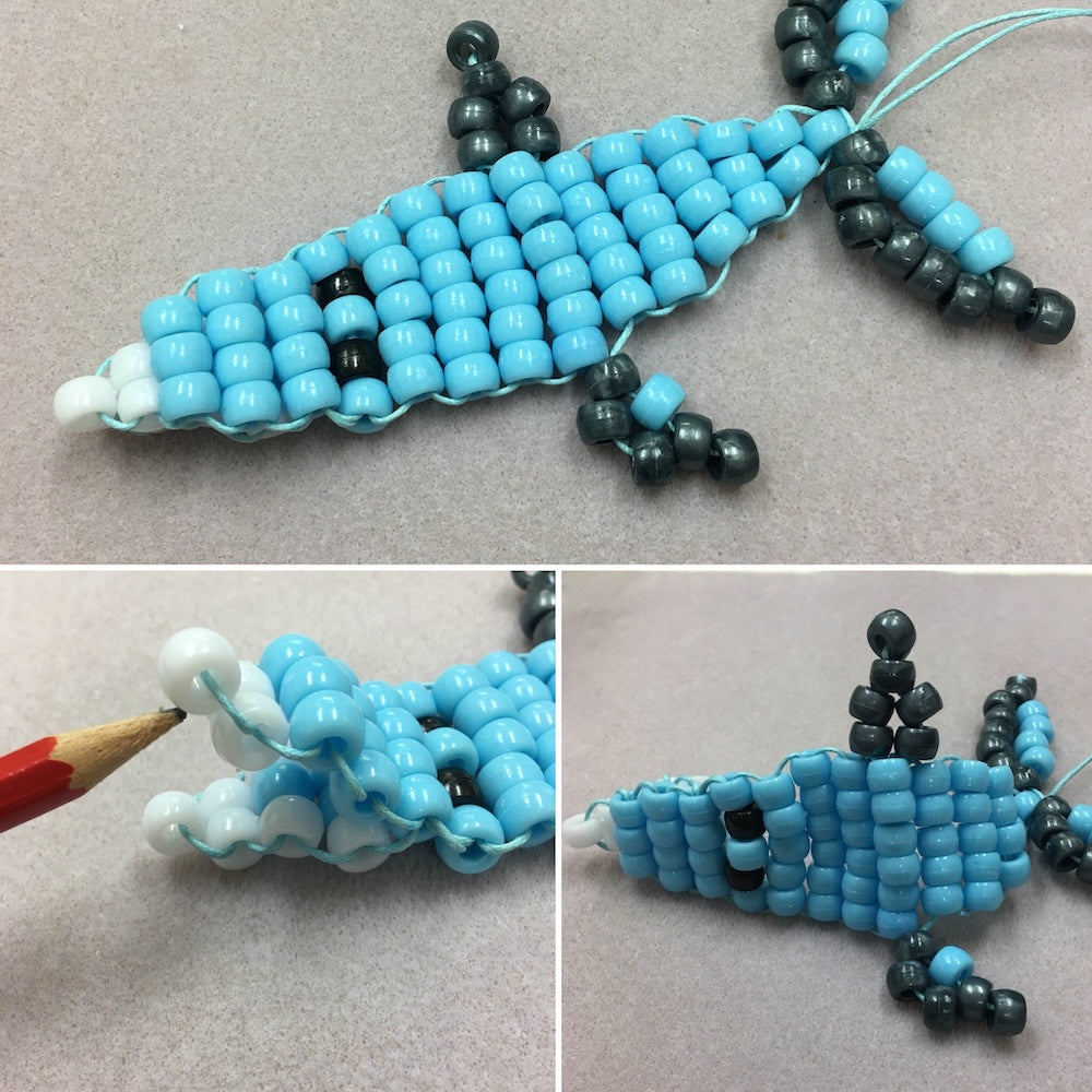 shark toy beaded from a kit in blue and grey pony beads with white beads for teeth on a grey textured background