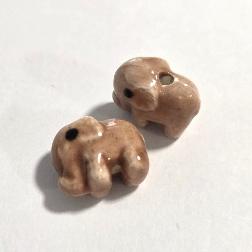 Two ceramic elephant beads on a white background