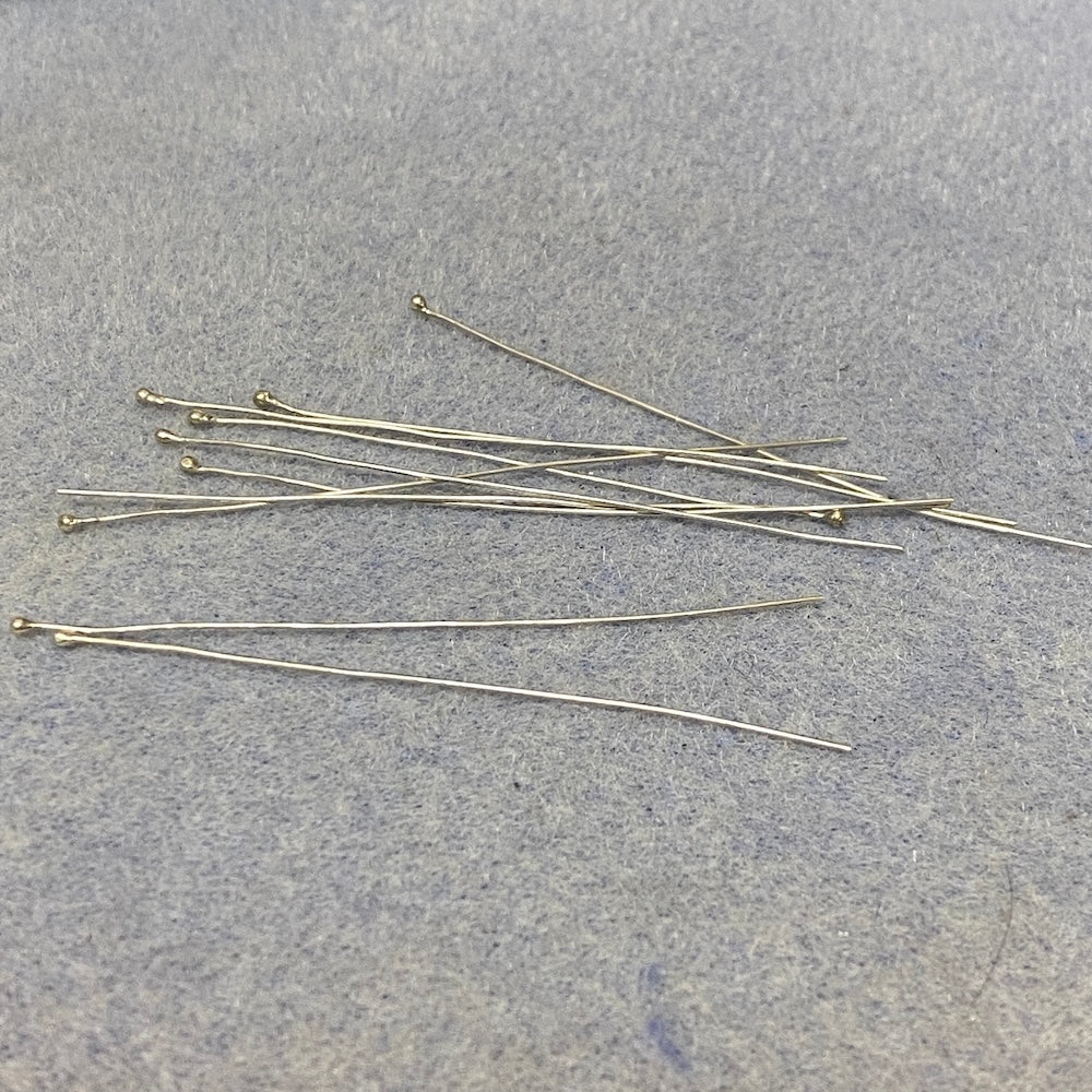 Set of sterling silver metal head pins on a gray surface