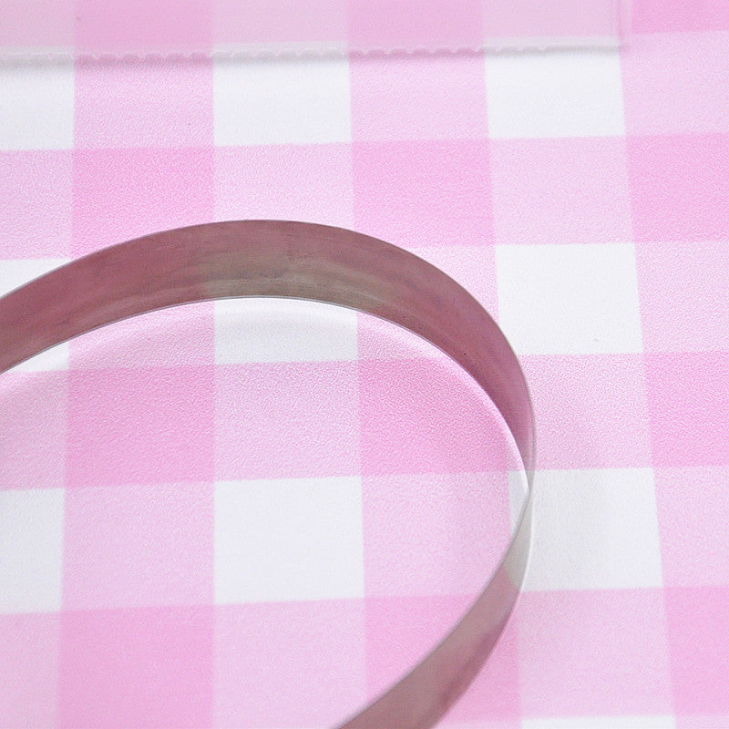 clay cutting blade being bent with plastic container on a pink and white checked background