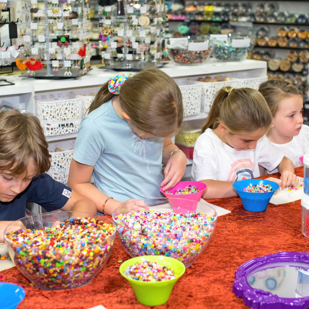 Children participating in a beading workshop at Bead Shack, with beads and crafting materials on the tables.