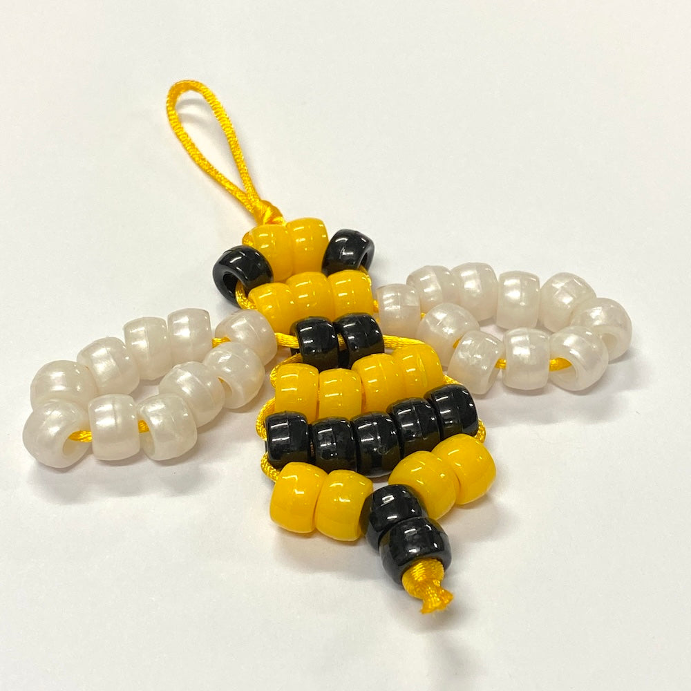 Bee toy made with a bead kit using yellow and black pony beads for the body and shiny white beads for the wings