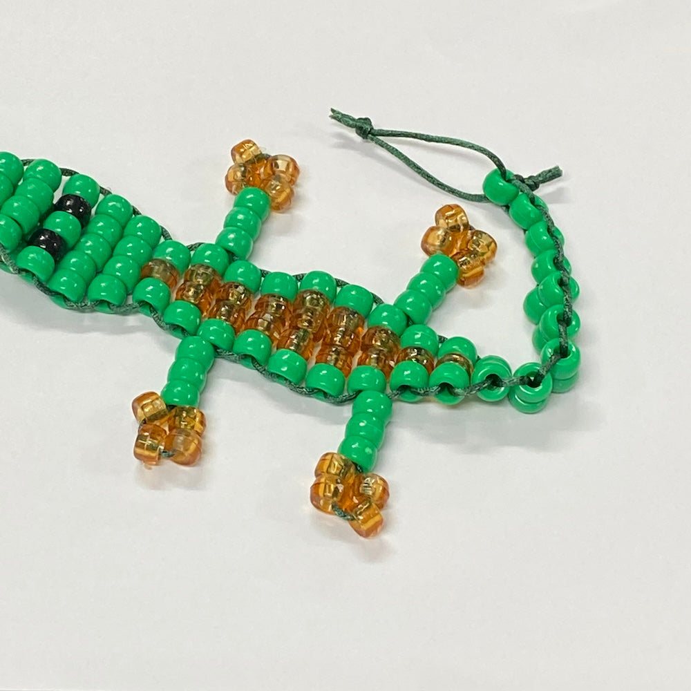alligator or crocodile beaded kit made into a toy using green and brown pony beads and green string on a white background
