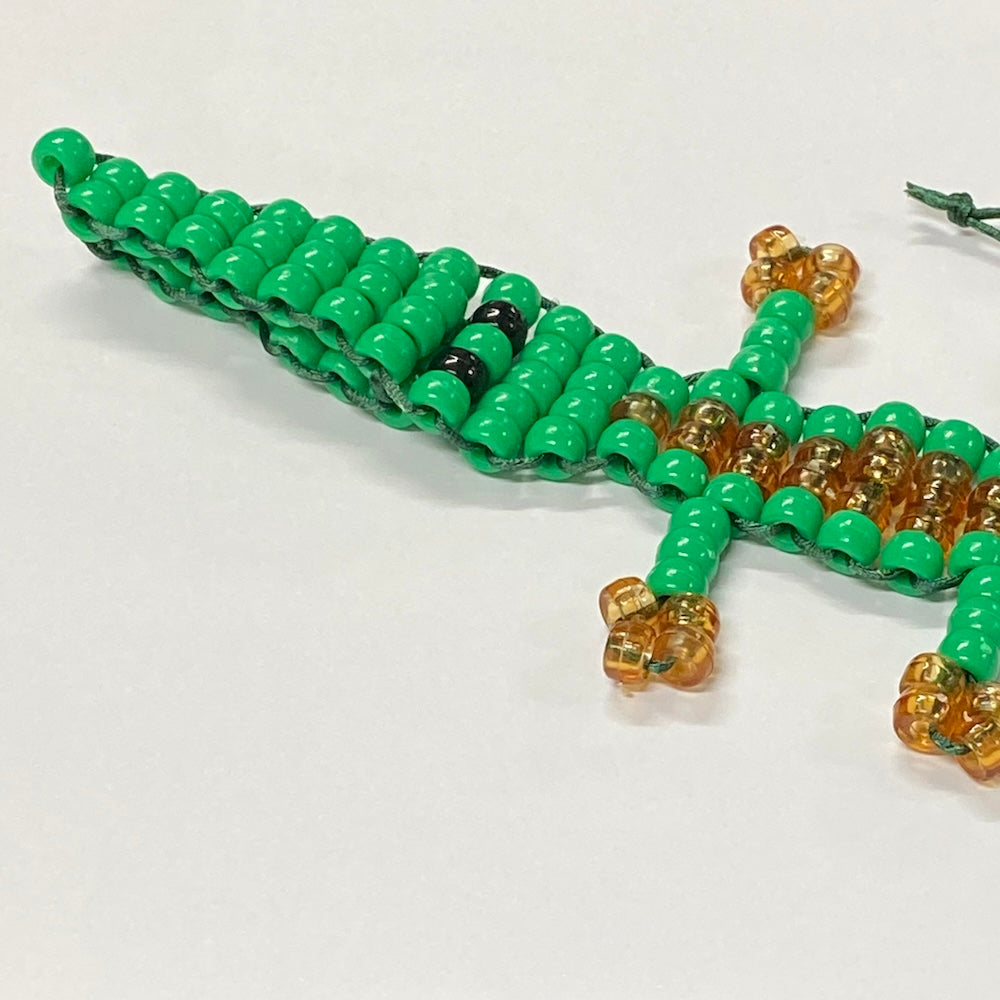 alligator or crocodile beaded kit made into a toy using green and brown pony beads and green string on a white background