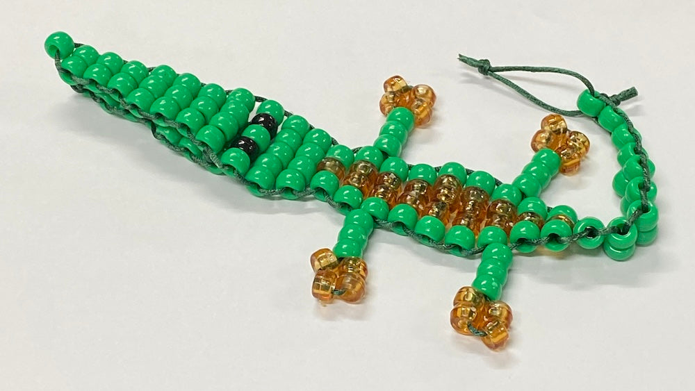 alligator or crocodile beaded kit made into a toy using green and brown pony beads and green string on a white background