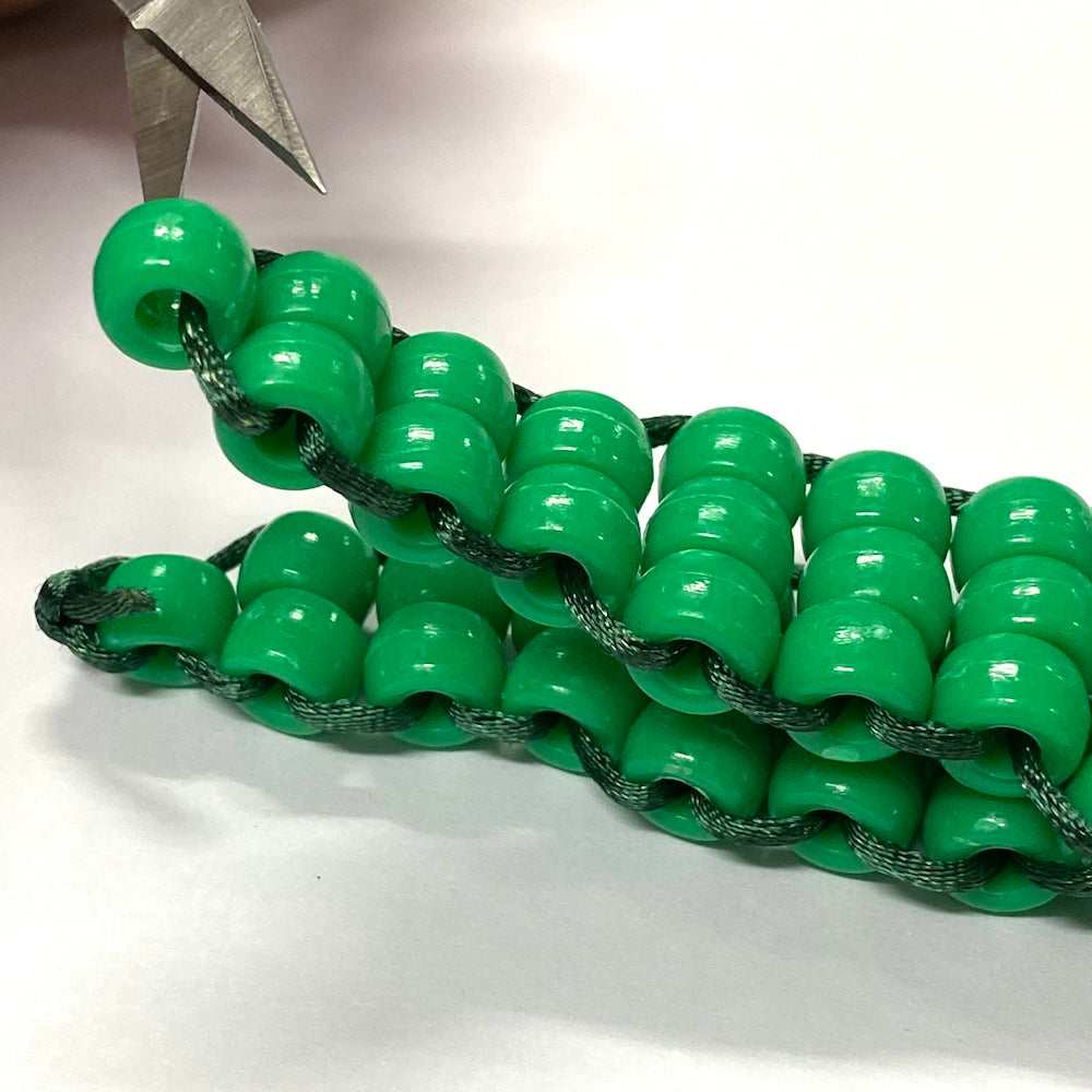 alligator or crocodile beaded kit made into a toy using green and brown pony beads and green string on a white background