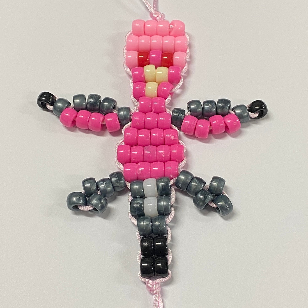 A beaded craft kit piece shaped like a galah, featuring pink, black, and gray beads on a white cord.