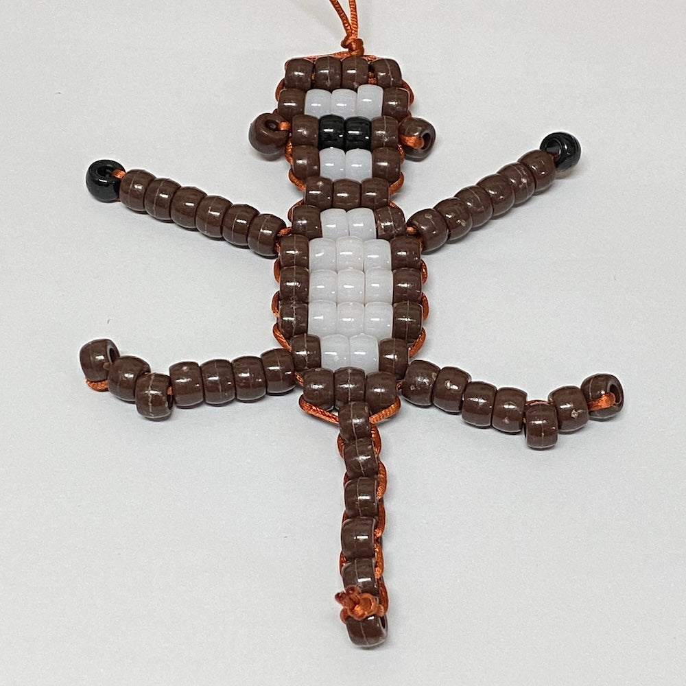 Beaded toy figure of a monkey made of brown, white, and black beads on a white background