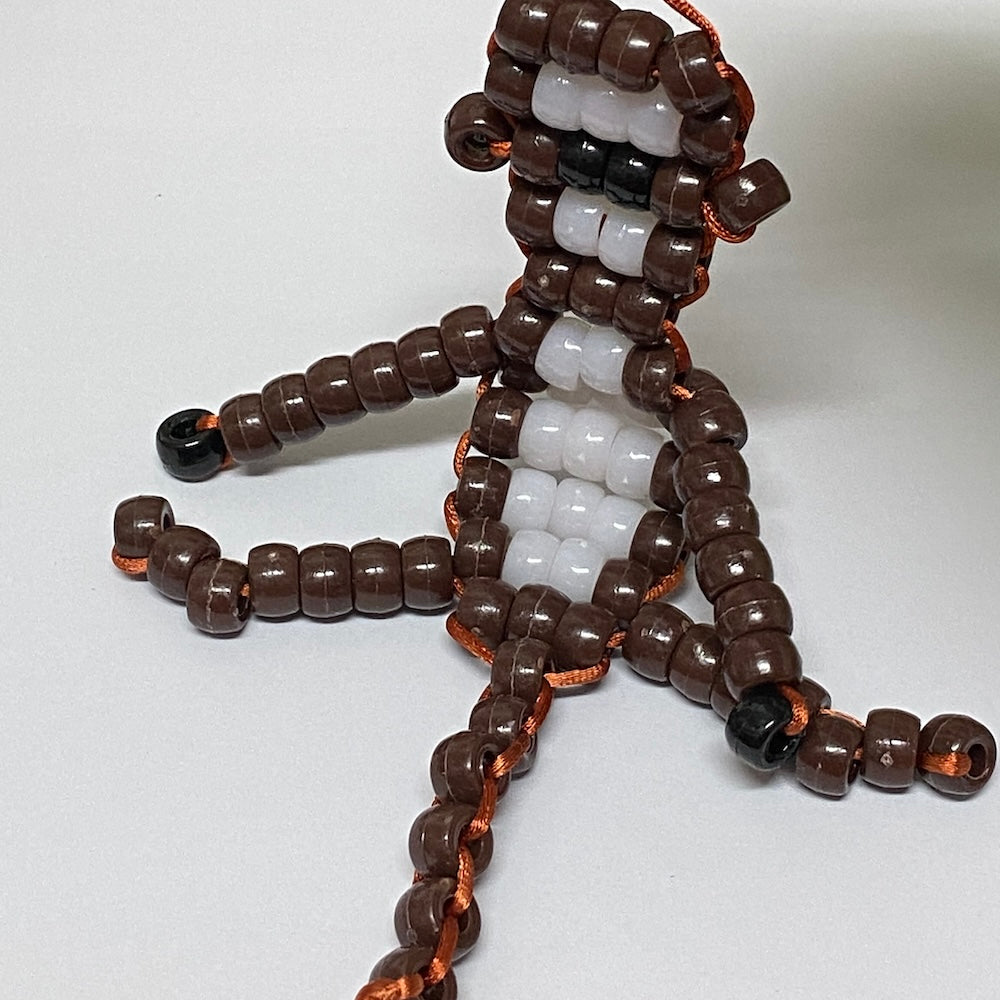 A bead and cord kit crafted into the shape of a monkey with brown and white colors.