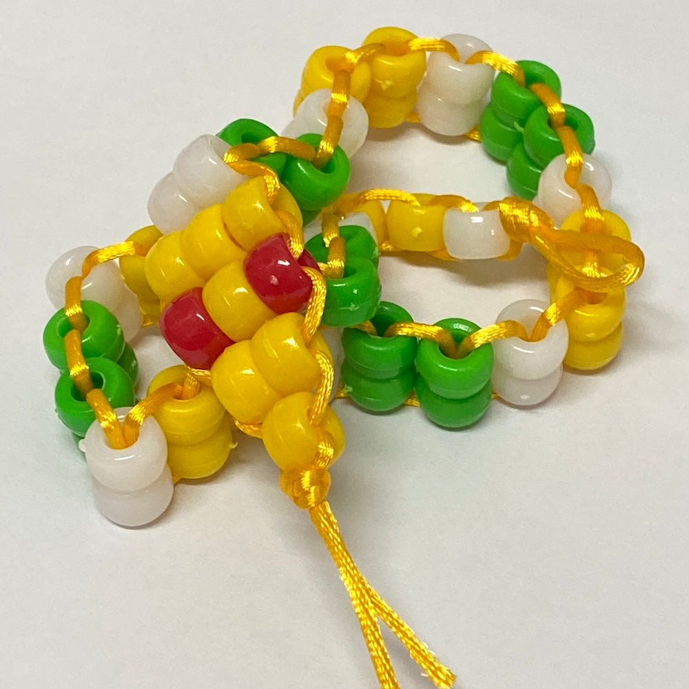 Colourful snake beaded toy made from a kit using pony beads in yellow green and white with red eyes on a white background