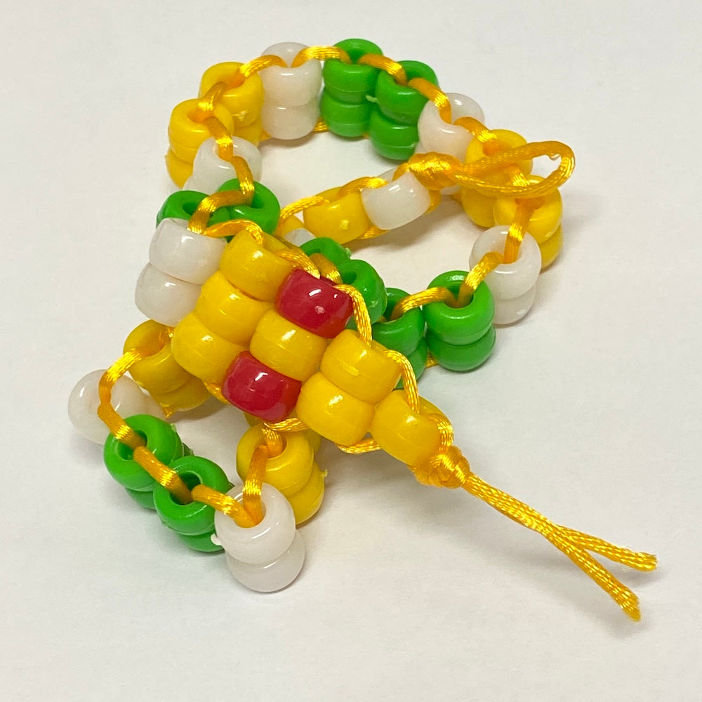 Colorful beaded snake toy with green yellow and white pony beads design on a white background